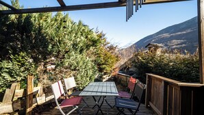An outdoor deck with a table and chairs, surrounded by trees and a mountain view. - Mountain house near Méribel (Brides-les-Bains)