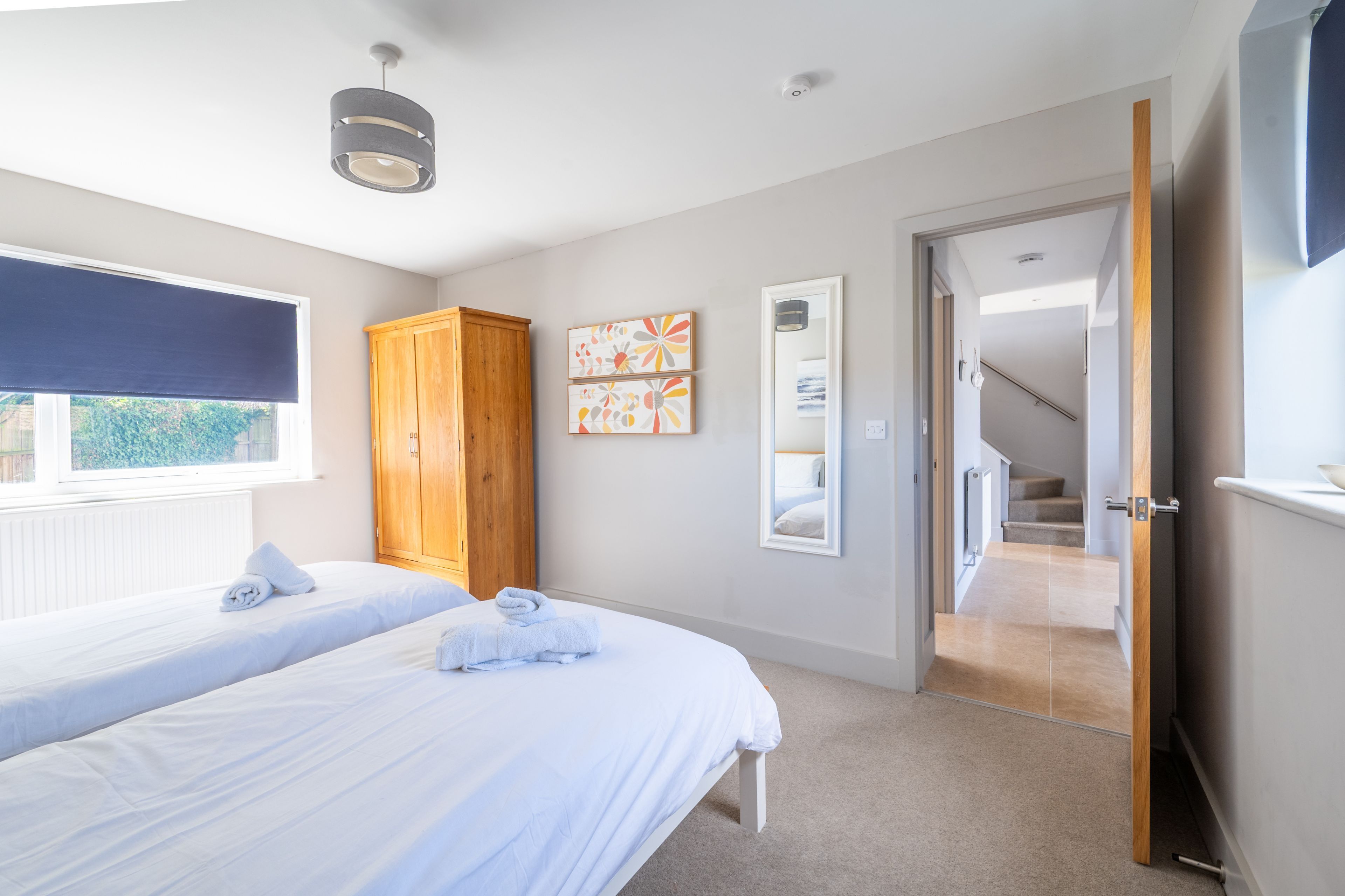 Een slaapkamer met twee bedden, een houten garderobe en een trap naar een verdieping erboven.