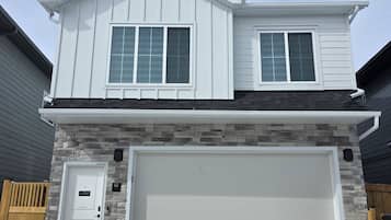 A two-story house with a garage, a stone facade, and a wooden door.