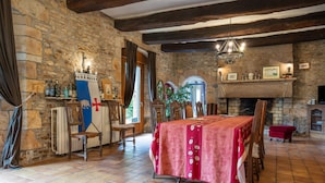 A stone-walled room with a fireplace, a dining table with a red tablecloth, and a chandelier. - Bed and Breakfast 'Galaad' with Shared Terrace, Shared Garden and Wi-Fi (Pluvigner)