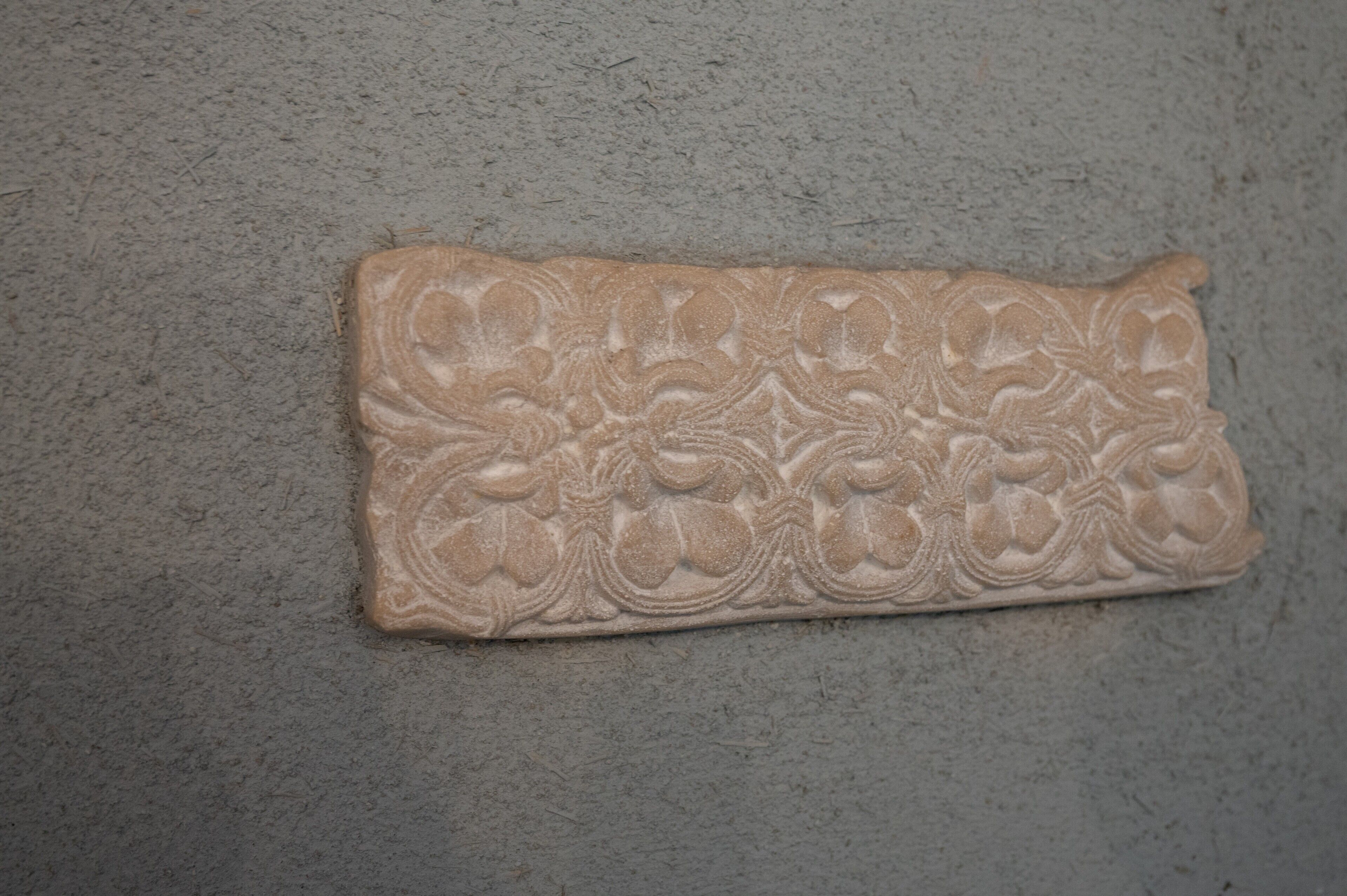 Un objet rectangulaire à la texture particulière, orné de motifs floraux sur un fond uni.