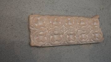 Un objet rectangulaire à la texture particulière, orné de motifs floraux sur un fond uni.