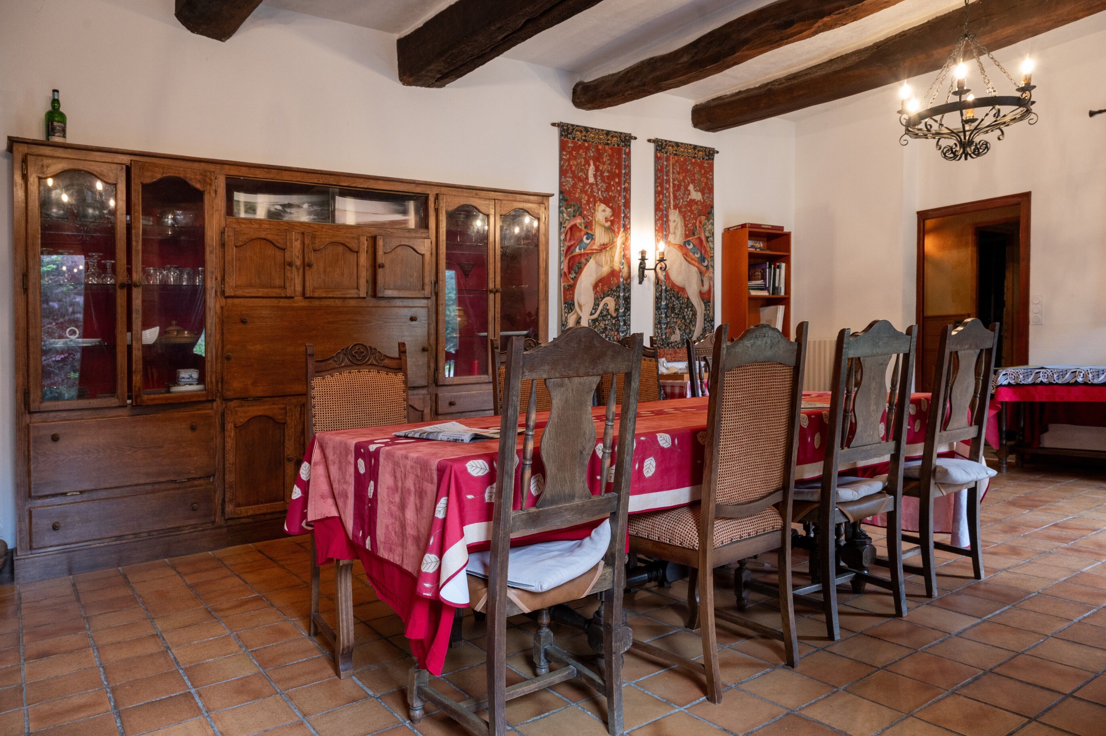 Un coin repas avec une table et des chaises en bois, un meuble avec des portes en verre et une tapisserie au mur.
