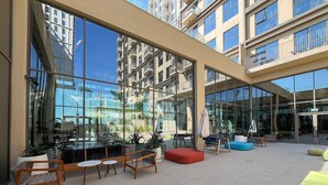 A spacious outdoor area with modern seating, large windows, and a view of surrounding buildings. - Modern 1BR at Collective | Dubai Hills Mall Nearby (Dubai)
