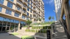 A modern building with multiple balconies, a staircase, and outdoor seating areas. - Modern 1BR at Collective | Dubai Hills Mall Nearby (Dubai)