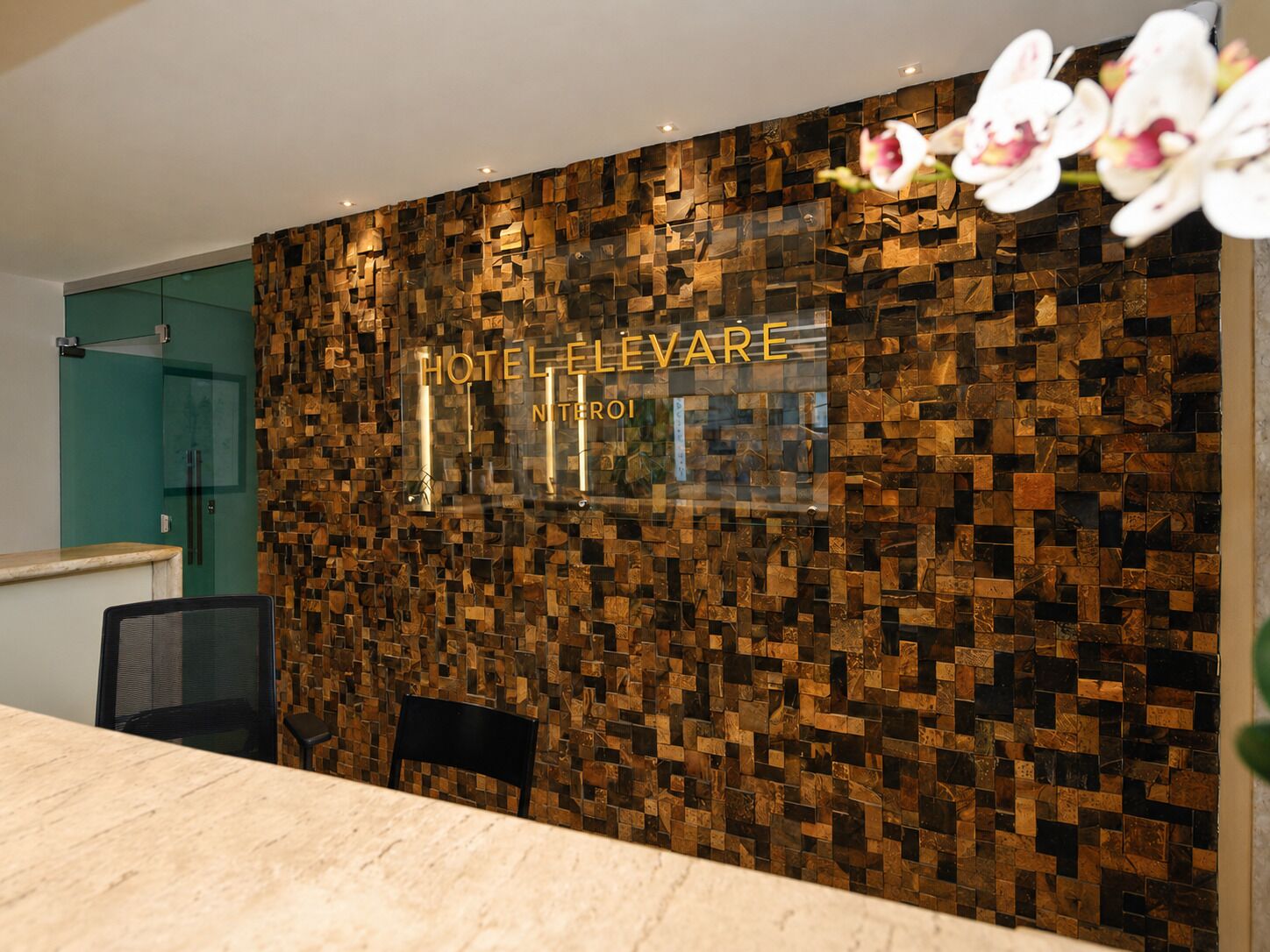 A reception desk with a mosaic wall, a glass door, and a chair.