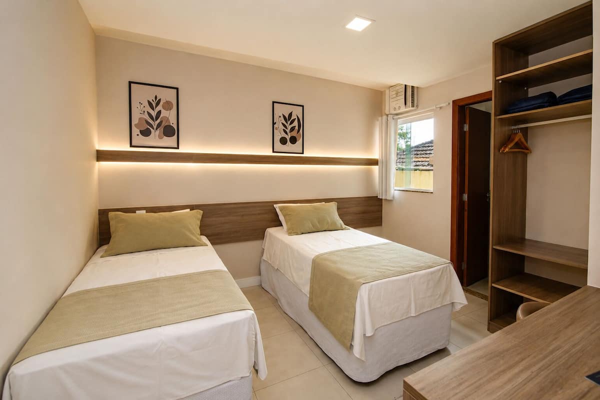 Een hotelkamer met twee bedden, een houten hoofdbord, een kledingkast en een raam.