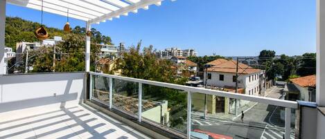 A balcony with a clear view of the cityscape, including buildings and greenery.
