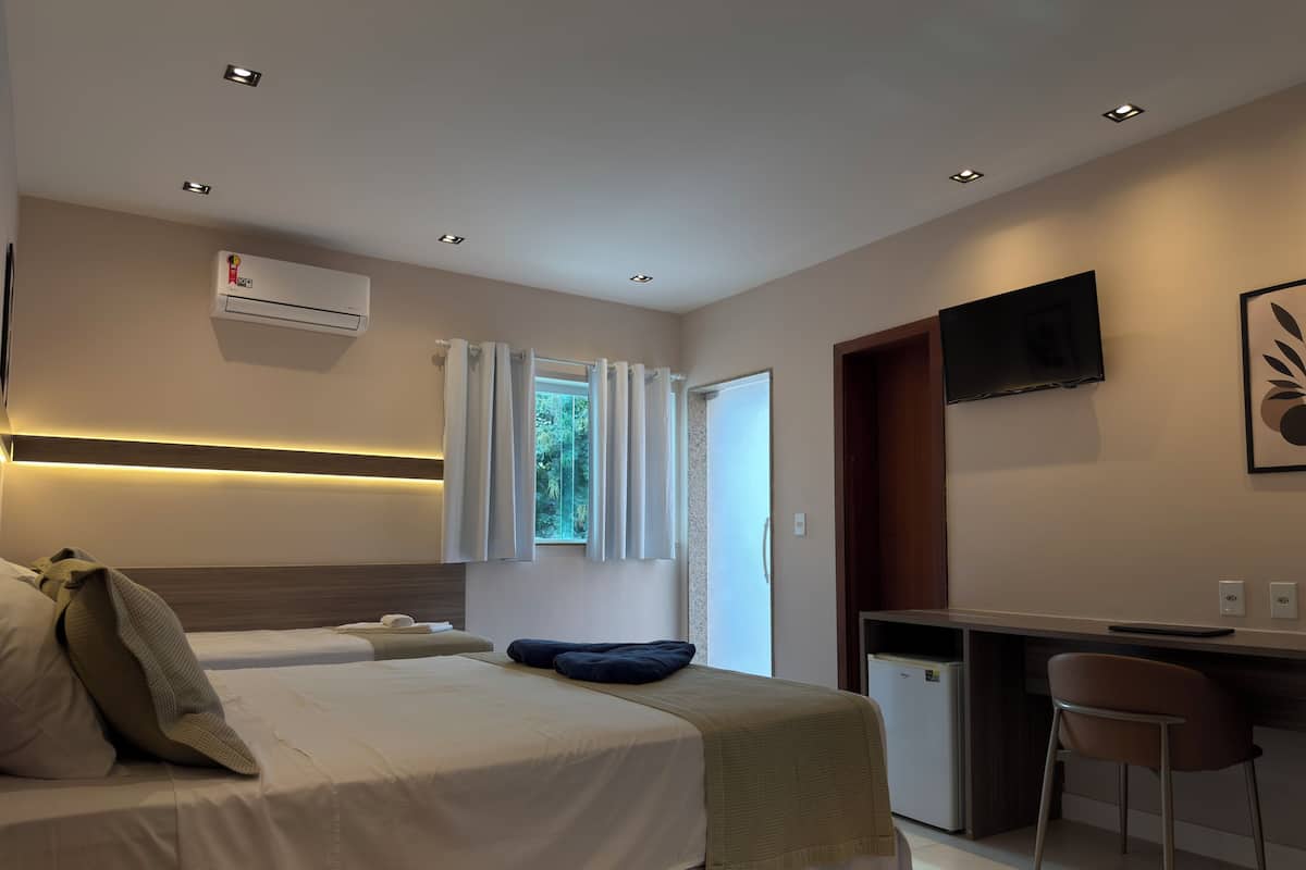 Een hotelkamer met twee bedden, een bureau, een televisie en een airconditioning.