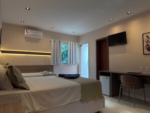 Een hotelkamer met twee bedden, een bureau, een televisie en een airconditioning.