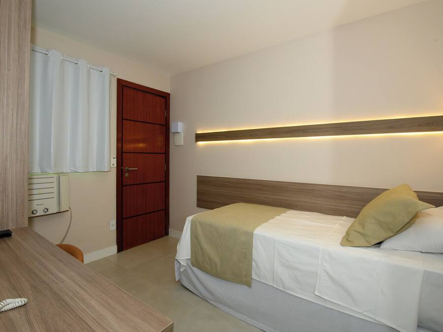 A single bed with a wooden headboard, a bedside table, and a wall-mounted light fixture.