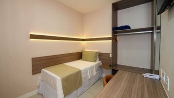 Una habitación de hotel pequeña con una cama individual, un escritorio y un armario empotrado.