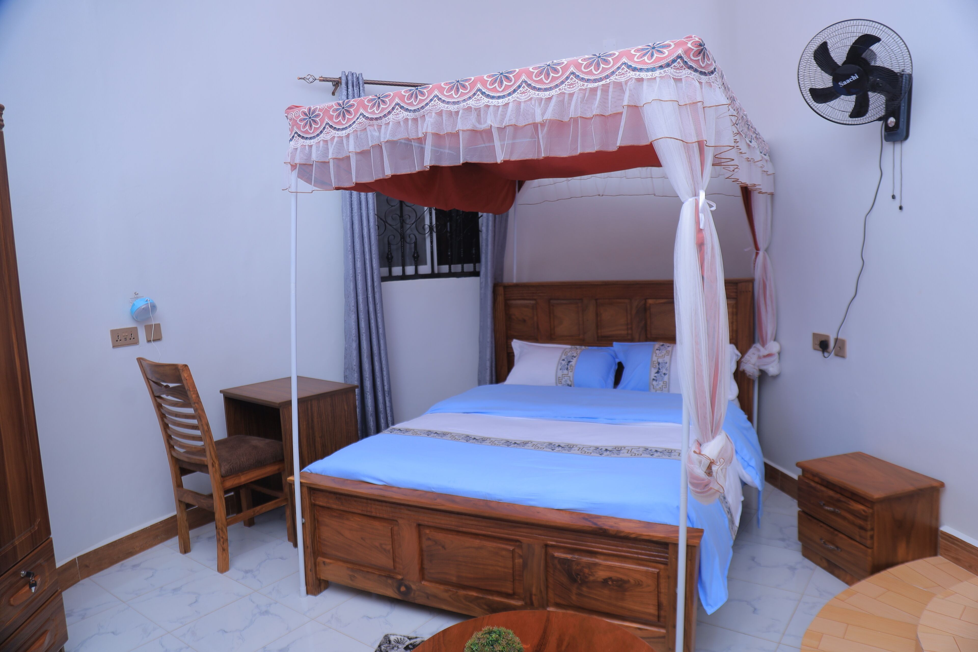 Un dormitorio con una cama de madera, una mesita de noche, una silla y una mesita auxiliar.