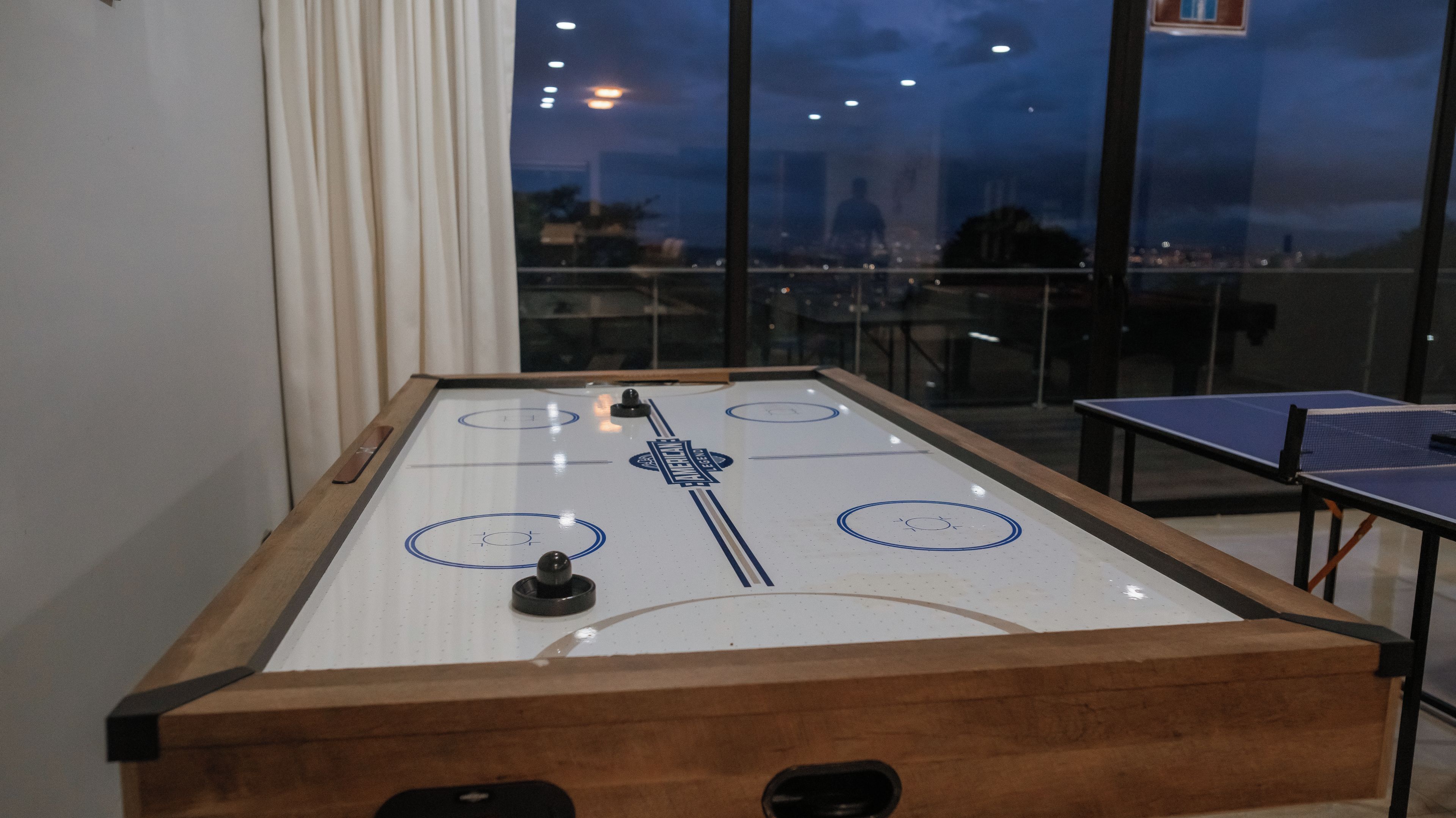 A foosball table with a city view through large windows.