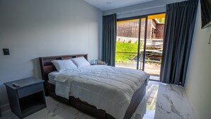 Un dormitorio con cama, mesita de noche y vistas a una terraza de madera a través de un ventanal corredero.