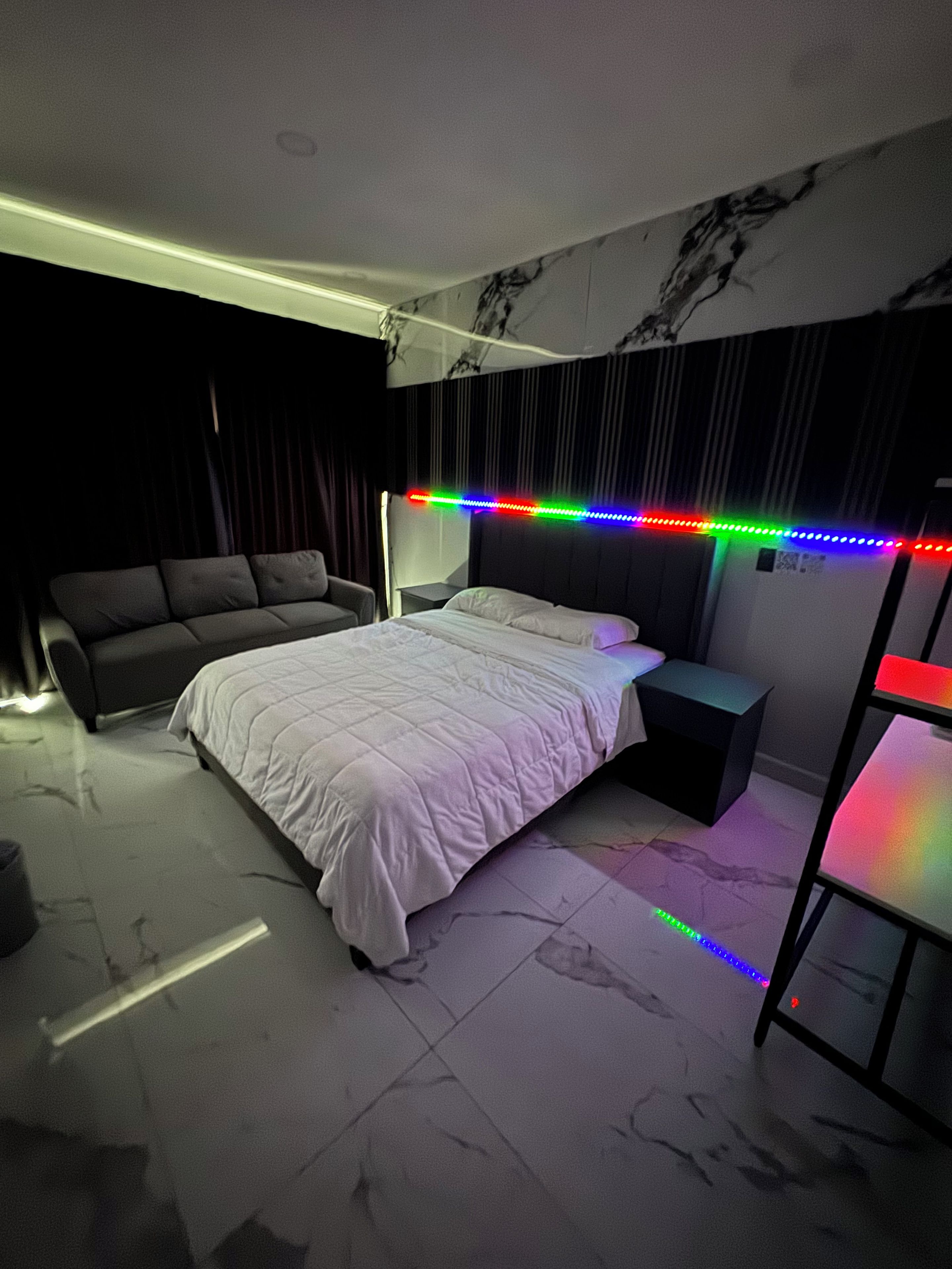 Ein modernes Schlafzimmer mit Bett, Nachttisch, Sofa und Schreibtisch.