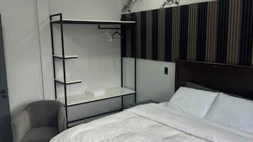 A modern bedroom with a large bed, a built-in wardrobe, a chair, and a marble-patterned wall.