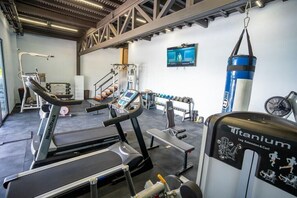 Un gimnasio con cintas de correr, máquinas de pesas y un saco de boxeo.