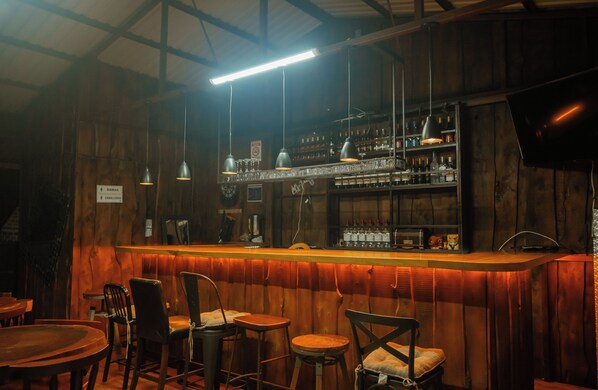 Un bar con paredes de madera, lámparas colgantes y una variedad de botellas en estanterías.