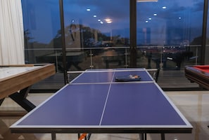A ping pong table in a room with large windows, a wooden table on the left, and a red table on the right. - Luxury Home Gym Jacuzzi Pool Suana Soccer Field and Tennis & Basketball Courts (Heredia)