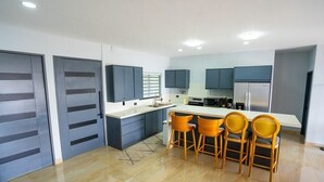 Una cocina moderna con armarios oscuros, una isla central con sillas y un refrigerador.