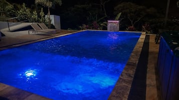 A swimming pool with a blue-lit water feature and a small waterfall.