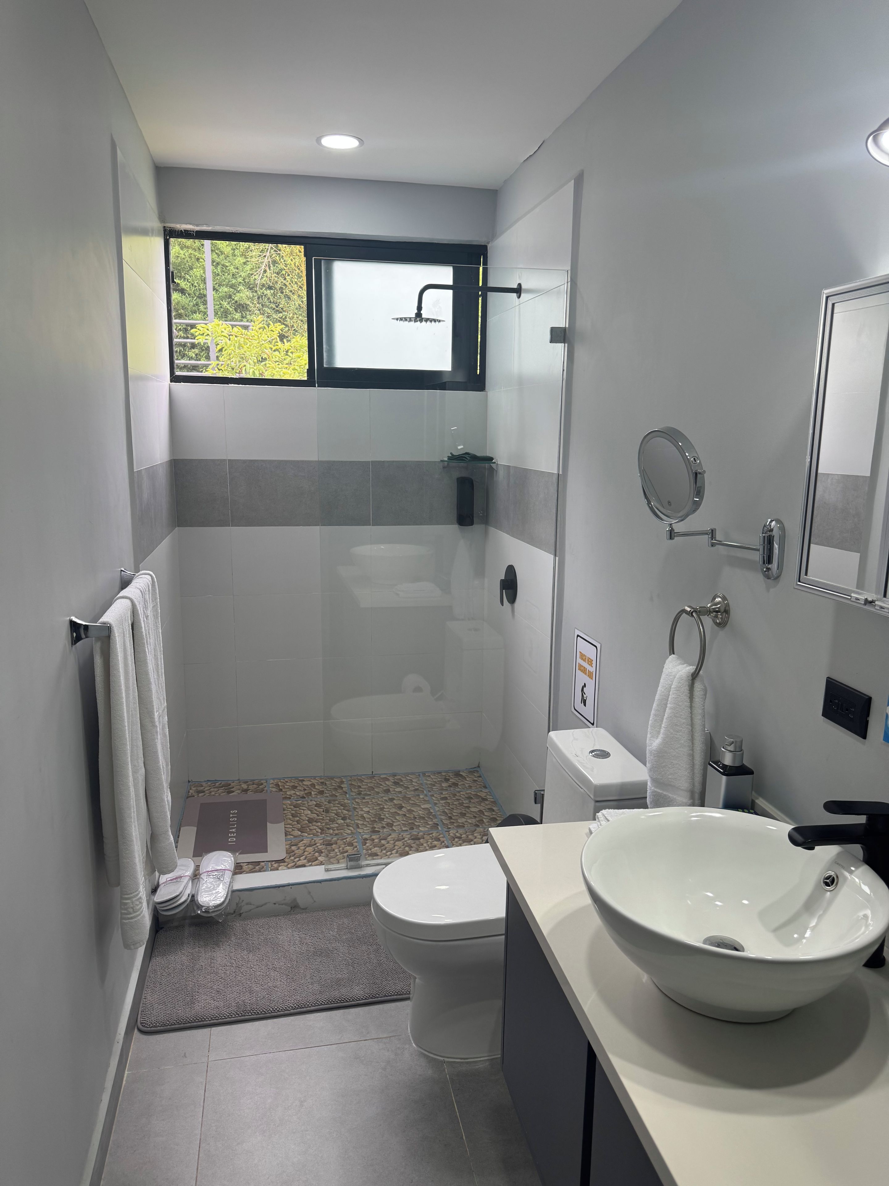 A modern bathroom with a shower, toilet, and sink.