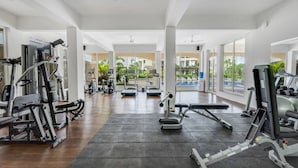 A spacious gym with various exercise machines, large windows, and a view of the outdoors. - 1BR in North Goa Pool Gym Clubhouse Access (Mapusa)