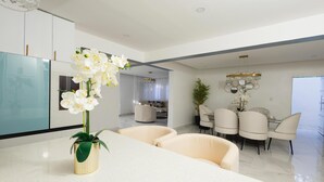 Una cocina moderna con armarios blancos, encimera de mármol y un jarrón con orquídeas blancas.