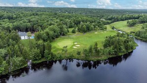A golf course with a water body, surrounded by dense forest. - Lakefront Luxury Retreat w Heated Pool Arcade (Hammonds Plains)