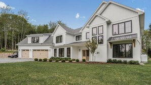 A modern two-story house with a large front lawn, garage, and a driveway. - Lakefront Luxury Retreat w Heated Pool Arcade (Hammonds Plains)