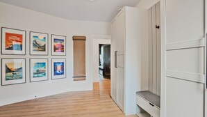 A hallway with framed travel posters on the wall, a wooden floor, and a white wardrobe. - Lakefront Luxury Retreat w Heated Pool Arcade (Hammonds Plains)