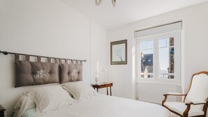 A bedroom with a bed, a chair, a nightstand, a window, and a framed picture on the wall. - House for 9 People, Cancale Port (Cancale)