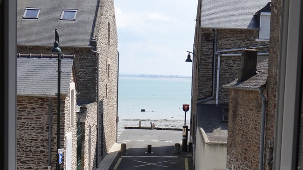 A view from a window overlooking a street leading to a beach with stone buildings and a clear sky. - House for 9 People, Cancale Port (Cancale)