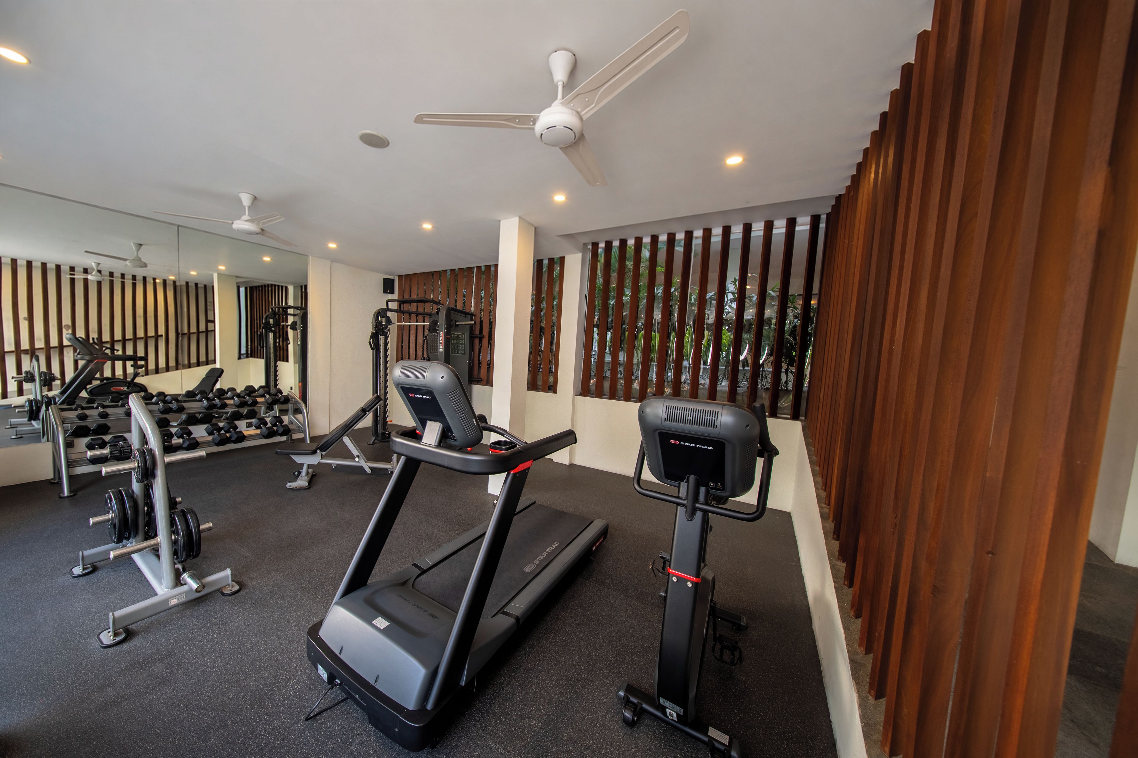 A gym with exercise equipment, including treadmills and weight machines, and a large mirror.