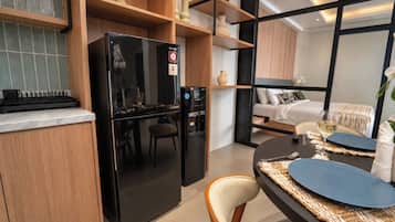 Cocina compacta con refrigerador negro, armarios de madera y comedor con mesa y sillas redondas.