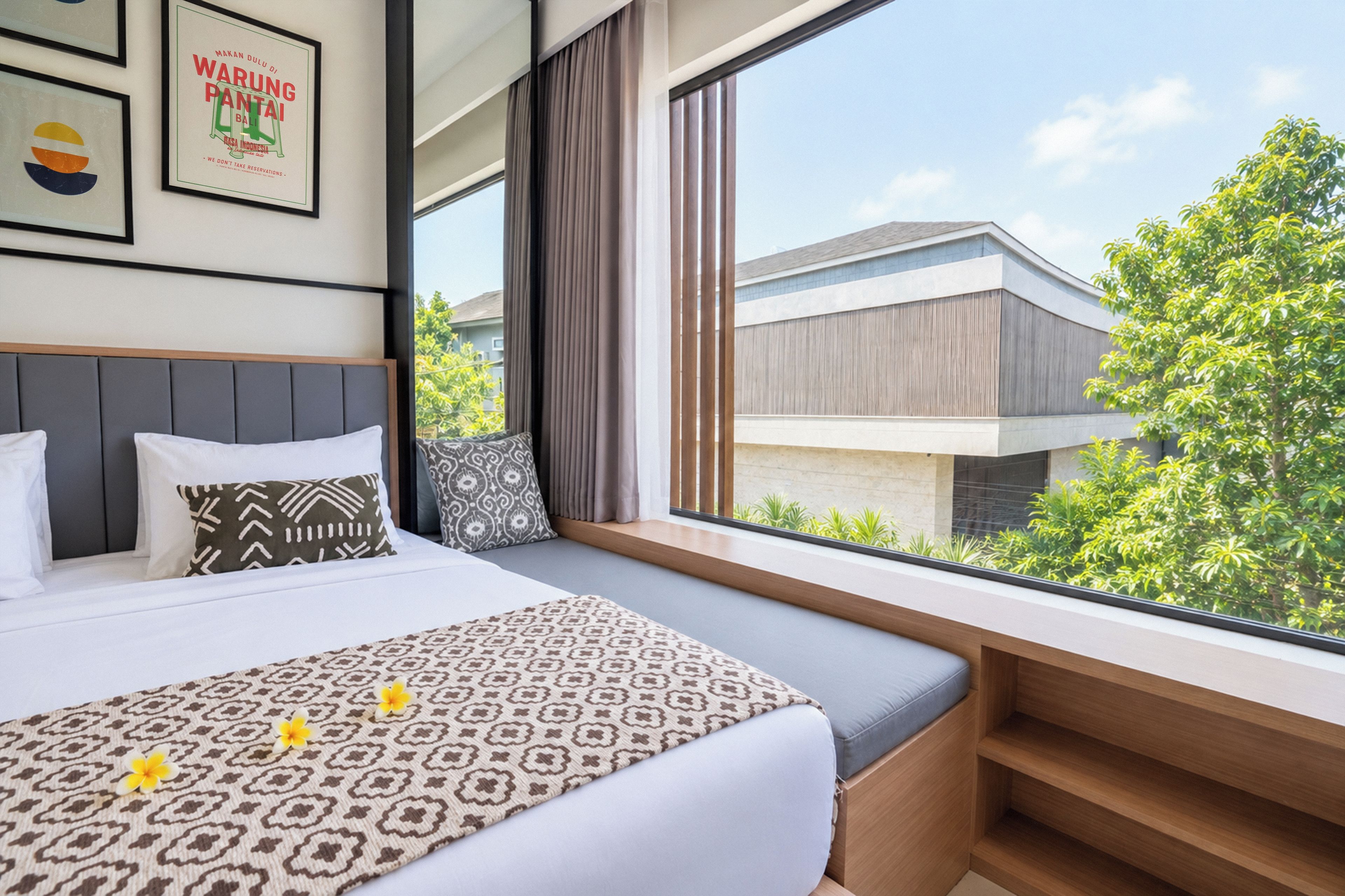 Ein Hotelzimmer mit einem großen Bett, einer Sitzgelegenheit am Fenster und Blick auf ein Gebäude und Bäume.