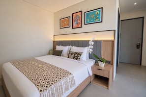 A modern hotel room with a large bed, a nightstand, a potted orchid, and three framed pictures on the wall. - TheNomad Canggu (Canggu)