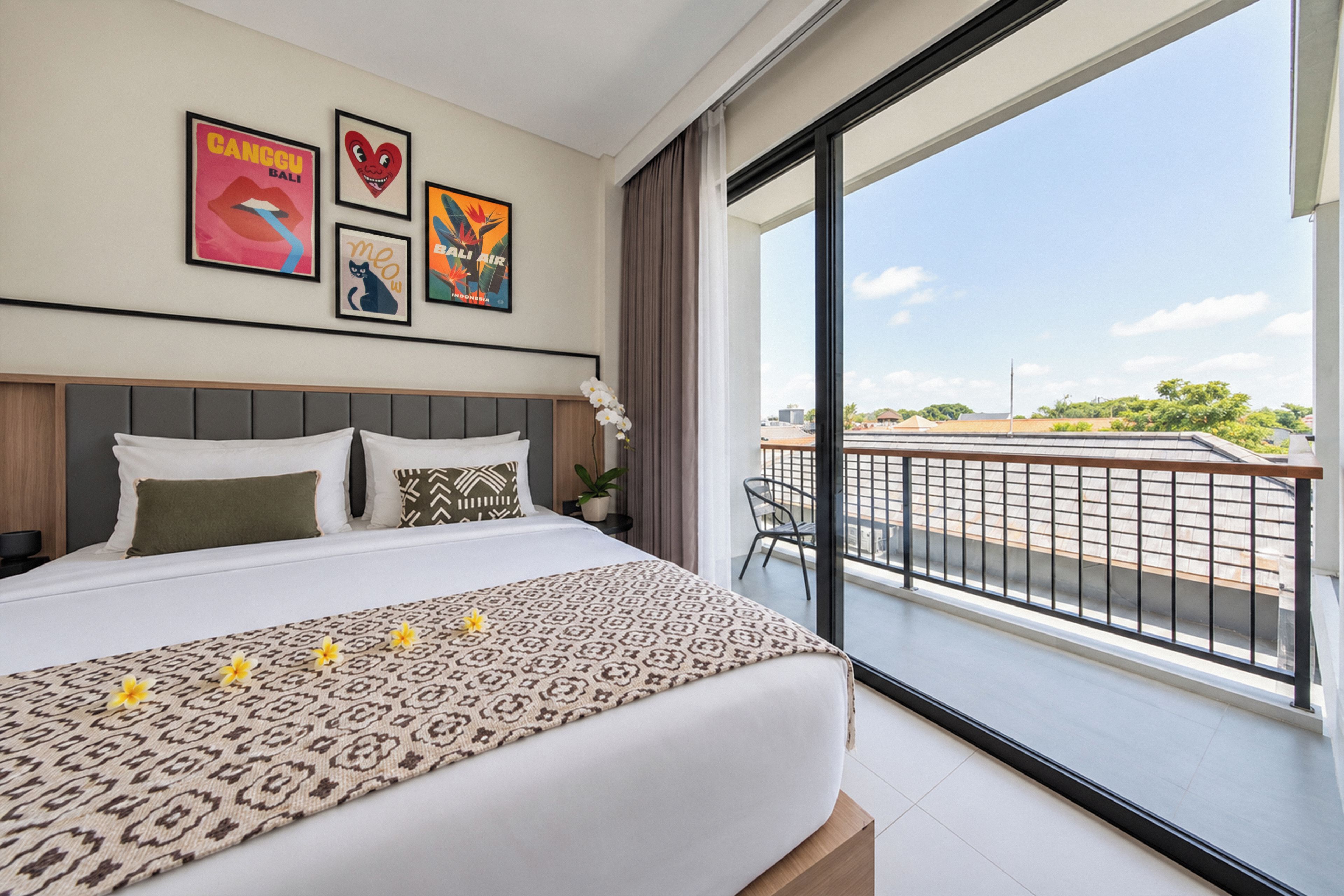 Een hotelkamer met een groot bed, een balkon met uitzicht en diverse decoraties aan de muur.