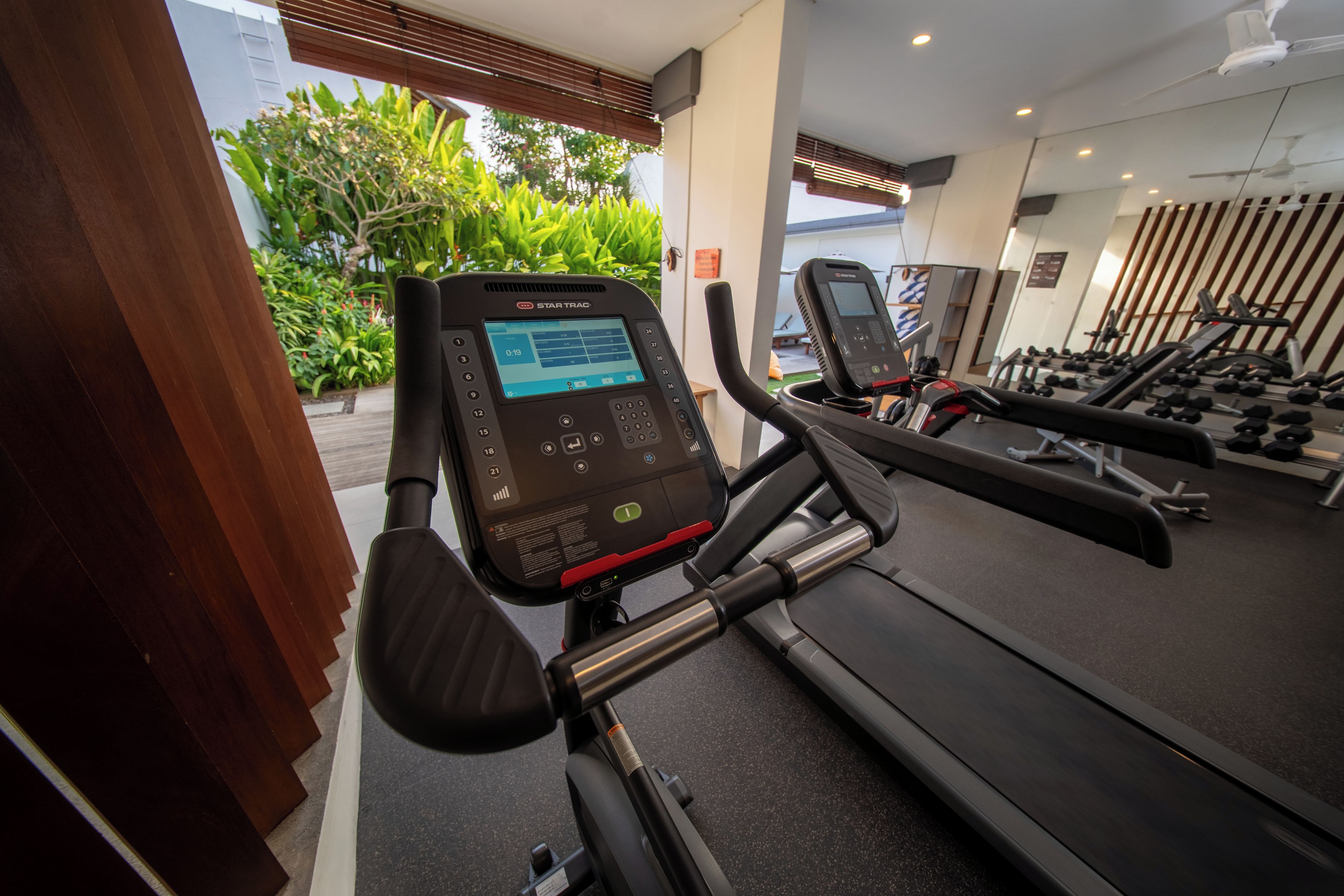 A gym with exercise equipment, including a treadmill and a stationary bike with a digital display.