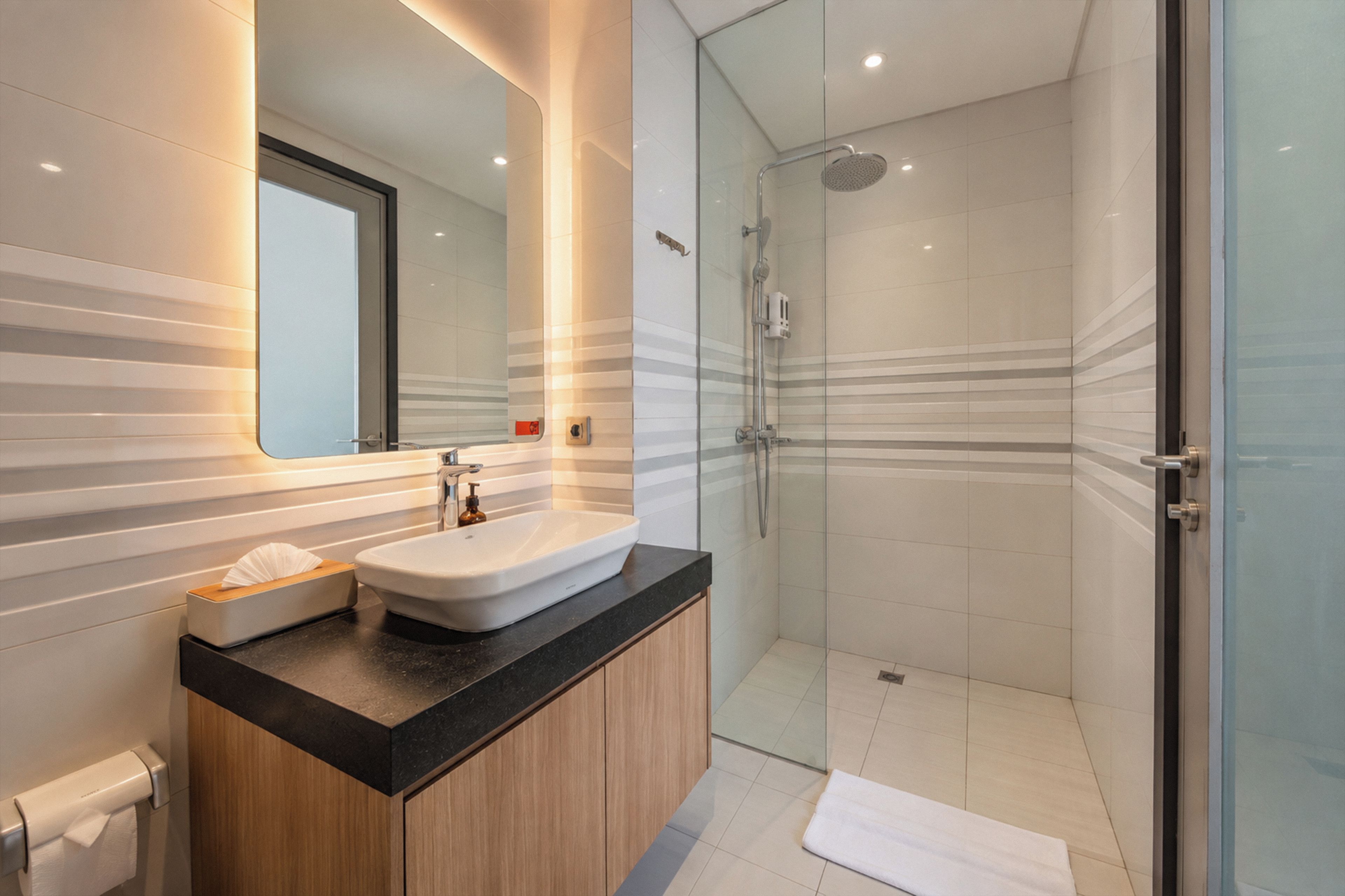 A modern bathroom with a glass-enclosed shower, a sink with a vanity, and a mirror.