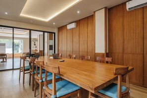 A conference room with a long wooden table, blue cushioned chairs, and a large window. - TheNomad Canggu (Canggu)