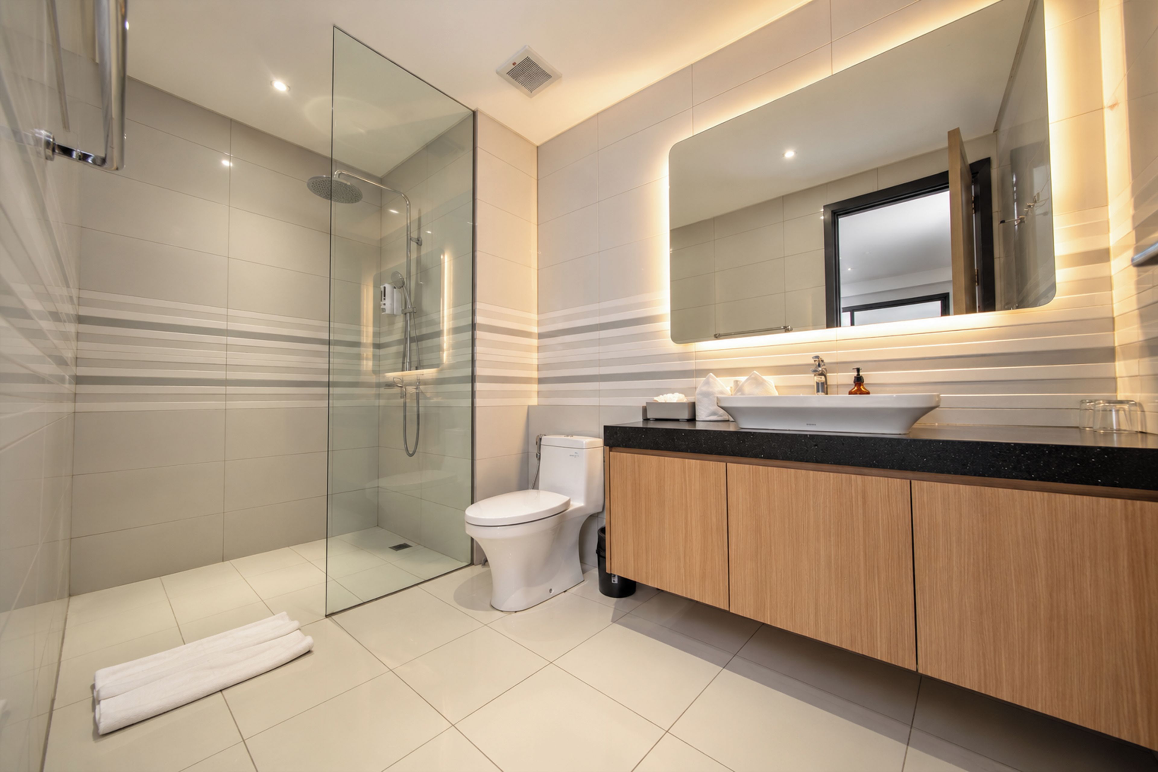 Un bagno moderno con doccia vetro, WC e mobile lavabo con specchio.