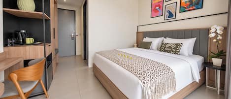 Une chambre d’hôtel avec un lit, un bureau et une chaise. On y trouve également des œuvres d’art murales et une plante en pot.