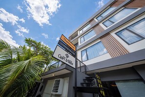 A modern building with multiple floors, a sign indicating a co-working space, and a Craft & Coffee establishment. - TheNomad Canggu (Canggu)