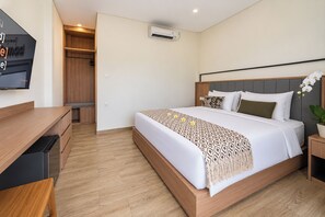 A hotel room with a bed, a desk, a wardrobe, and an air conditioning unit. - TheNomad Canggu (Canggu)