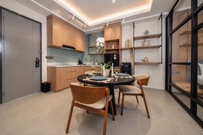 A modern kitchen with wooden cabinets, a dining table with chairs, and a built-in oven. - TheNomad Canggu (Canggu)