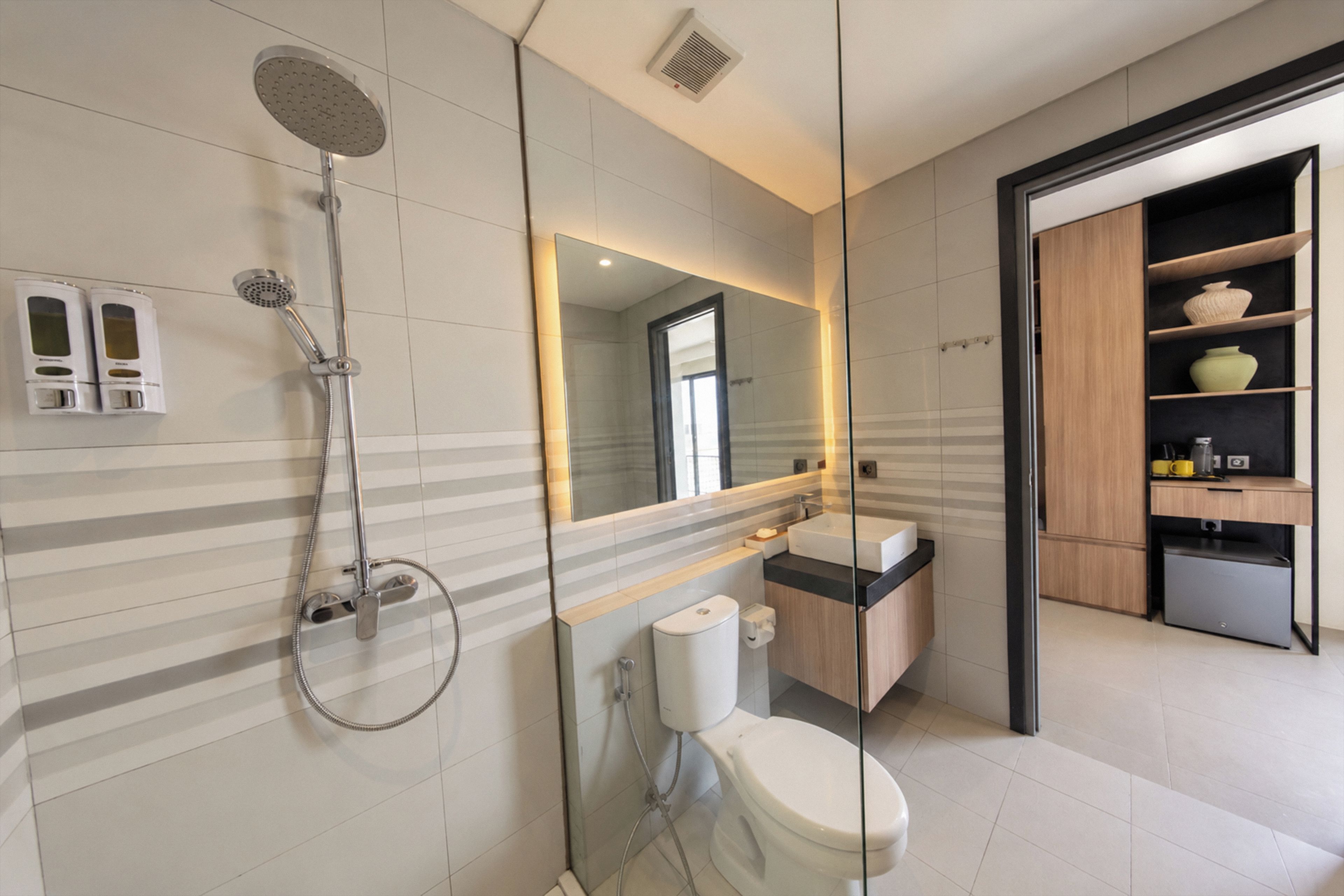 Un baño moderno con ducha, inodoro, lavabo y un espejo grande.