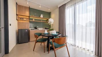 A modern kitchen with a dining area, featuring a refrigerator, cabinets, and a table with chairs.