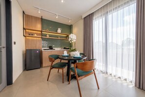 Une cuisine moderne avec un coin repas, comprenant un réfrigérateur, des placards et une table avec des chaises.